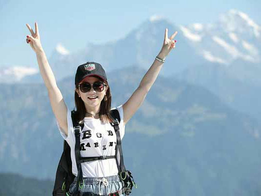 Hiker with raised arms against a mountain backdrop