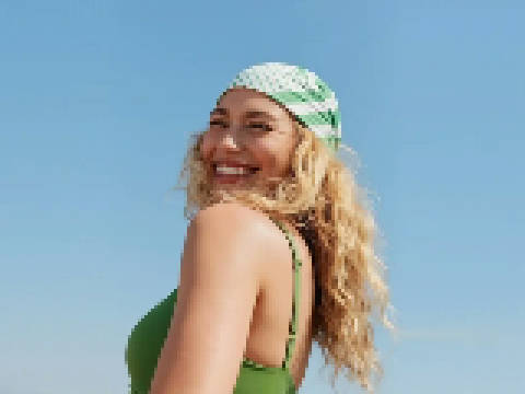 Soft low-resolution photo of a smiling woman with curly blonde hair and a green striped bandana before AI upscaling