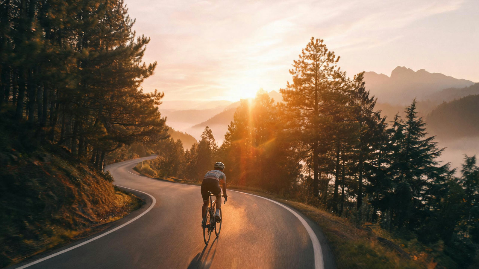 Film still from a generated video: a cyclist descending a mountain road at dawn